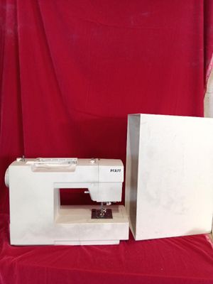 a white sewing machine sitting on a table next to a red cloth