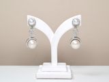pair of white pearl and crystal earrings on a white stand