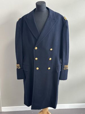 un manteau bleu à boutons dorés posé sur un présentoir pour mannequin