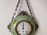 a clock hanging from a chain on the wall