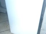 a small white refrigerator sitting on the floor in the kitchen