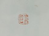 a red stamp on the bottom of a white plate