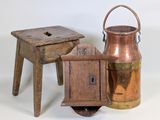 deux tabourets en bois et un pichet en cuivre sur fond blanc