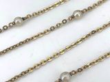 a close up of a gold chain with pearls on it