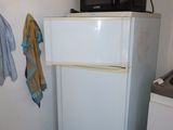 a small refrigerator in a small kitchen with a microwave on top of it