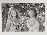 black and white photograph of two women standing next to each other in front of trees