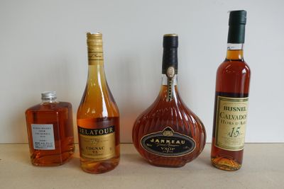 trois bouteilles d'alcool sont alignées sur un plan de travail