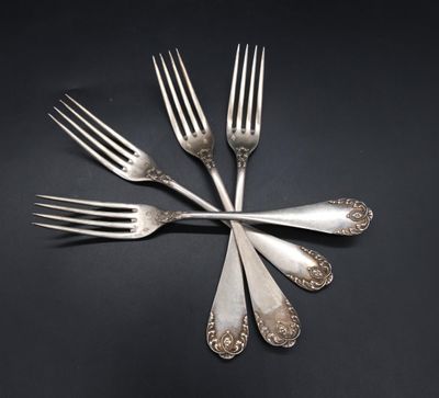 four forks are arranged in a circle on a black surface