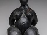 une image représentant une statue d'une femme assise sur une balle