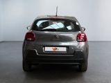 the back of a silver car in a room with a white wall