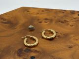 deux paires de boucles d'oreilles créoles en or posées sur une table en bois