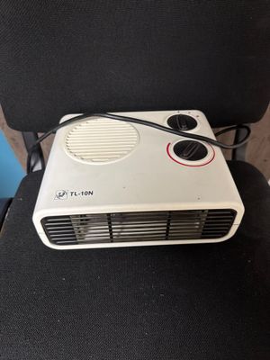 un petit radiateur soufflant posé sur une chaise noire
