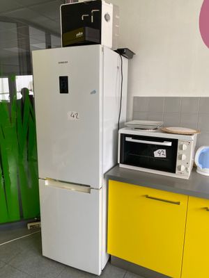 un réfrigérateur et un micro-ondes dans une cuisine aux placards jaunes