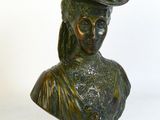 buste en bronze d'une femme coiffée d'un chapeau, sur fond blanc
