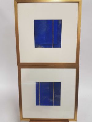une paire de tableaux encadrés bleus et blancs posés sur un socle en bois