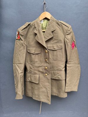 une vieille veste militaire suspendue à un cintre accroché au mur