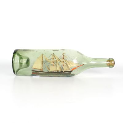 une bouteille en verre contenant un bateau, posée sur une surface blanche