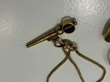 a small brass object on a white surface next to a clock