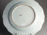 a white plate with a gold rim sitting on a stand