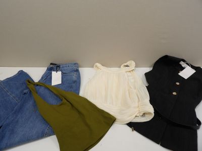 trois paires de jeans et une veste sont posées sur une table blanche