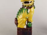 figurine de chien jaune assise sur une boîte et portant un collier vert