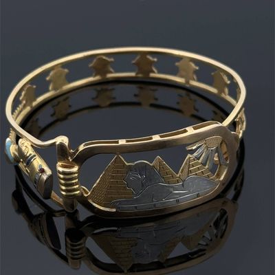 un gros plan d'un bracelet en or orné d'un paysage de montagne