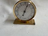 une petite horloge dorée posée sur une surface blanche