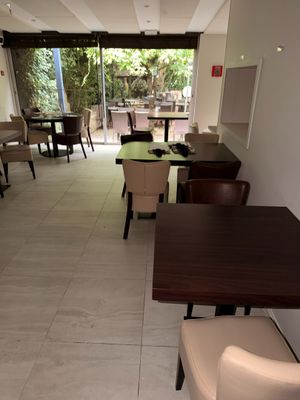 tables and chairs are lined up in a restaurant with a view of the outside