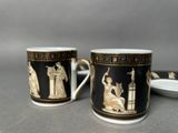 pair of black and gold coffee mugs with figures on them