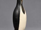 une figurine de pingouin en noir et blanc sur fond gris
