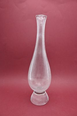 a clear glass vase on a stand on a red background