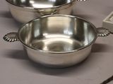 two silver bowls sitting on a table with spoons