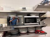 a man taking a picture of a microwave in a kitchen
