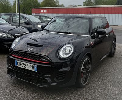 une Mini Cooper noire garée sur un parking à côté d'autres voitures