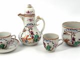 four cups and a teapot sitting on a table