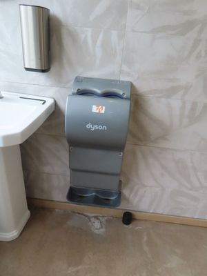 a bathroom with a toilet, sink and a paper towel dispenser