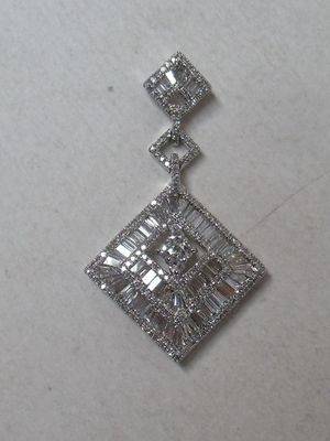 a close up of a diamond pendant on a white surface