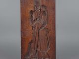une plaque en bois sculptée représentant un homme tenant un bâton