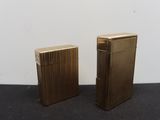 two gold lighters sitting next to each other on a black surface