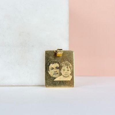 un pendentif plaqué or sur lequel figure la photo de deux personnes