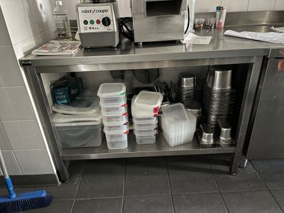 une cuisine équipée d'un plan de travail en inox sur lequel est posé un micro-ondes