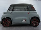 a small grey car with red rims parked in a garage