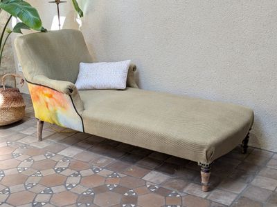 a chaise lounger sitting on a tiled floor next to a potted plant