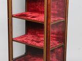 une vitrine ancienne recouverte de velours rouge et ornée de passementeries dorées