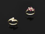 two gold rings with pink and white stones on a black surface