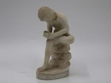 statue of a man sitting on a rock with his hands on his knees