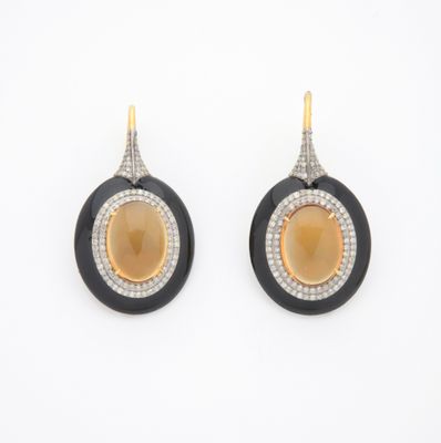 une photo d'une paire de boucles d'oreilles noires et dorées ornées de diamants