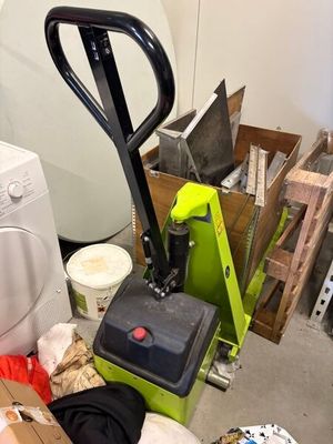 une photo d'une pièce encombrée où l'on voit une machine à laver et une pile de cartons