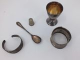 a silver cup, spoon, and spoon rest on a table