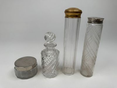 trois bouteilles en verre et un récipient en métal posés sur une surface blanche